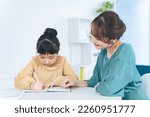 Small photo of Asian woman teaching little girl. Mother and daughter. Cram school. Tutor.