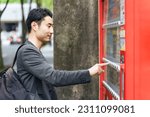 Small photo of Asian man buying drinks from vending machine.