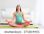 Pregnant woman exercising on green mat in room