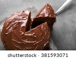 Chocolate cake with a cut piece and blade on gray background, closeup