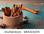 Wooden bowl with cinnamon sticks and anise on table