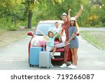 Happy family next to car in countryside
