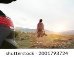 rear view of an asian photographer traveling by car looking at view in the morning sunlight with camera in hand