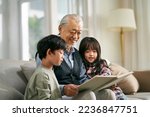 Small photo of asian grandfather having a good time telling story to cute grandson and granddaughter