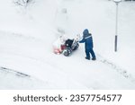 cleaning snow in the yard in winter, a janitor with a snowblower cleans the street