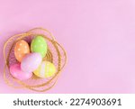 Happy Easter holiday greeting card concept. Colorful Easter Eggs and spring flowers on pastel pink background. Top view, flat lay, copy space.
