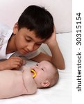 Small photo of stepbrother - asian boy looking on caucasian baby girl