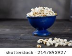 A wooden bowl of salted popcorn at the  wooden table