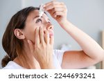 Young woman putting eye drops at home 