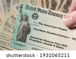 Stack of 20 dollar bills with US Treasury illustrative check to illustrate American Rescue Plan Act of 2021 payment on cash background