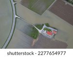 Small photo of AERIAL TOP DOWN: Church with cemetery is inaccessible due to flooded access road. Village church on a dry island surrounded by muddy flood water and submerged farmland after abundant autumn rainfall.