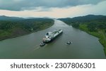 Small photo of Escorted cargo ship travels between two oceans through Panama Canal waterway. Strategic man-made water shortcut divides Central and South America and enables shortening of routes for maritime traffic.