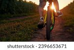 Small photo of Child rides bicycle, close-up. Child legs spin pedals. Kid rides into sunset, spinning bicycle wheel. Kid dream of riding bike. Sports lifestyle. Happy family in park. Child bike ride in nature, sun