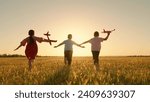 Small photo of Happy children run with toy plane across field at sunset. Boy, girl wants to become pilot, an astronaut. Children play with toy plane