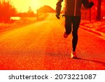 Small photo of red toned portrait of unrecognizable woman trains by running the streets of the town, the weather is cold but she faces reality and keeps fit anyway