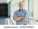 Small photo of Senior executive in the bright corridor of a large company observes his interlocutor with an expression of suspicion and inquisitiveness. He seems to demand an explanation.