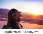 Image of pretty woman walking in snowy mountains, side view of cute girl looking up, closeup portrait of female wearing warm winter earmuff, red sunset, wintertime sports, trekking and hiking concept