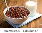 chocolate cereals in bowl and milk on wooden table