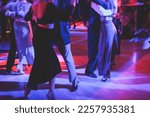 Couples dancing traditional latin argentinian dance milonga in the ballroom, tango salsa bachata kizomba lesson in the red and purple lights, dance festival
