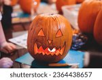 Small photo of Process of making pumpkin lantern for halloween party, glowing jack-o-lantern carving master class on halloween fair market, orange decoration, illuminated carved pumpkin lanterns