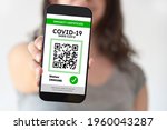Small photo of Unrecognizable young woman showing on her smartphone screen a certificate of immunity against Covid19. Concept of travel and health protocols during the corona virus pandemic.