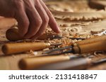 Small photo of Craftsman carving with a gouge. Woodwork. Workbench with equipment. Wood carving tools. Chisels for carving