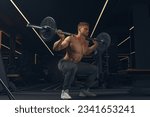 Muscular man doing squats with barbell in a gym. Male bodybuilder doing workout Confident young man doing barbell workout in gym Powerful attractive man.