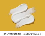 White cosmetic cream lotion swatch smear smudge on yellow color background.	