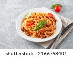 Pasta Spaghetti Bolognese in white plate on grey background. Bolognese sauce is classic italian cuisine dish. Popular italian food.