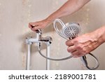 Small photo of Plumber fixing leaky single handle shower faucet in bathroom.