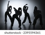 Small photo of In the shot on a black background in the light of a spotlight in the silhouette. Dance group consisting of attractive girls. They show dance moves towards jazz funk.