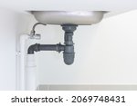 Drain pipe or sewer under kitchen sink. Pvc plastic pipe and
 flexible supply tube connection to stainless steel sink include faucet, trap for drain water and waste in drainage and plumbing system.