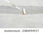 Small photo of Renovation or construction work. To using roller to painting mortar cement or finishing material for repair crack, skim coat or improvement surface of concrete pavement floor or slab for driveway.