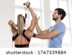 Young woman during workout with a personal fitness instructor using rubber  resistance bands in the gym.