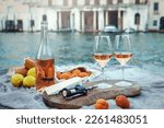 Rose wine, fruits and snacks on the wooden pier during picturesque picnic on the wooden gondola dock