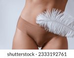 Female belly and soft feather. Concepts of body cosmetics and  hair removal treatment.