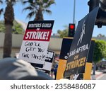 Small photo of LOS ANGELES, CA, AUG 15, 2023: member of the Writers Guild of America holds "God'll get you for this" placard, picketing with other striking writers and actors at Paramount Pictures