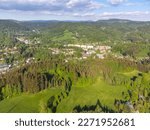 Desna v Jizerskych horach town in the middle of green hills of Jizera mountains on sunny summer day. Czech Republic. Aerial view from drone.