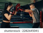 Small photo of A man practices attack in boxing wit a help of a woman holding pads