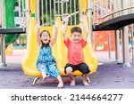 Asian child smiling playing on slider bar toy outdoor playground, happy preschool little kid having funny while playing on the playground equipment in the daytime in summer, Little girl boy climbing
