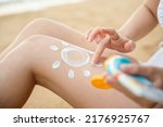Small photo of Beautiful Asian woman apply sun protection cream on tanned on leg at tropical beach with white sand, Sun Cream Skincare, Close up female in bikini using sunscreen lotion on back body before sunbathing