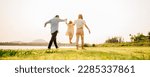 Small photo of Back view of Happy Asian family walking and playing together in a scenic garden, with a beautiful sunset in the background and a feeling of fun and enjoyment, Family day