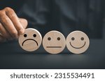 Small photo of Negative customer experience concept. Holding frown icon on wooden circle, customer expresses dissatisfaction and disappointment. Illustrating bad review, low score, and unsatisfied customer.