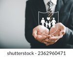 Supporting family futures, Businessman protective gesture complements young family silhouette. Health and house insurance icons symbolize protection, reinforcing family life insurance.
