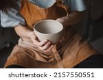 Pottery studio, artisan business, female potter hands holding ceramic bowl ready for firing in a kiln