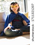 Small photo of lonely superhero child dressed up with mask meditating, finding inner peace into thyself with yoga and mindfulness for peaceful corona lockdown, low angle view