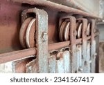 Small photo of a photography of a rusted metal door with a pulley on it, there are two pulleys on the side of a rusted metal wall.