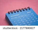 Small photo of November 2022 - small spiral desktop calendar against textured paper, low angle macro shot, time and business concept