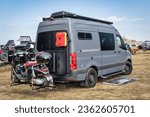 Small photo of Loveland, CO, USA - August 26, 2023: 4x4 camper van on Mercedes Sprinter chassis with Vespa scooter on a hitch rack in a busy campground.