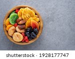 Dried fruits and berries on a wooden bowl top view. Raisins, kiwi, cherries, plums, dried apricots, dates, pineapples, figs, melon.